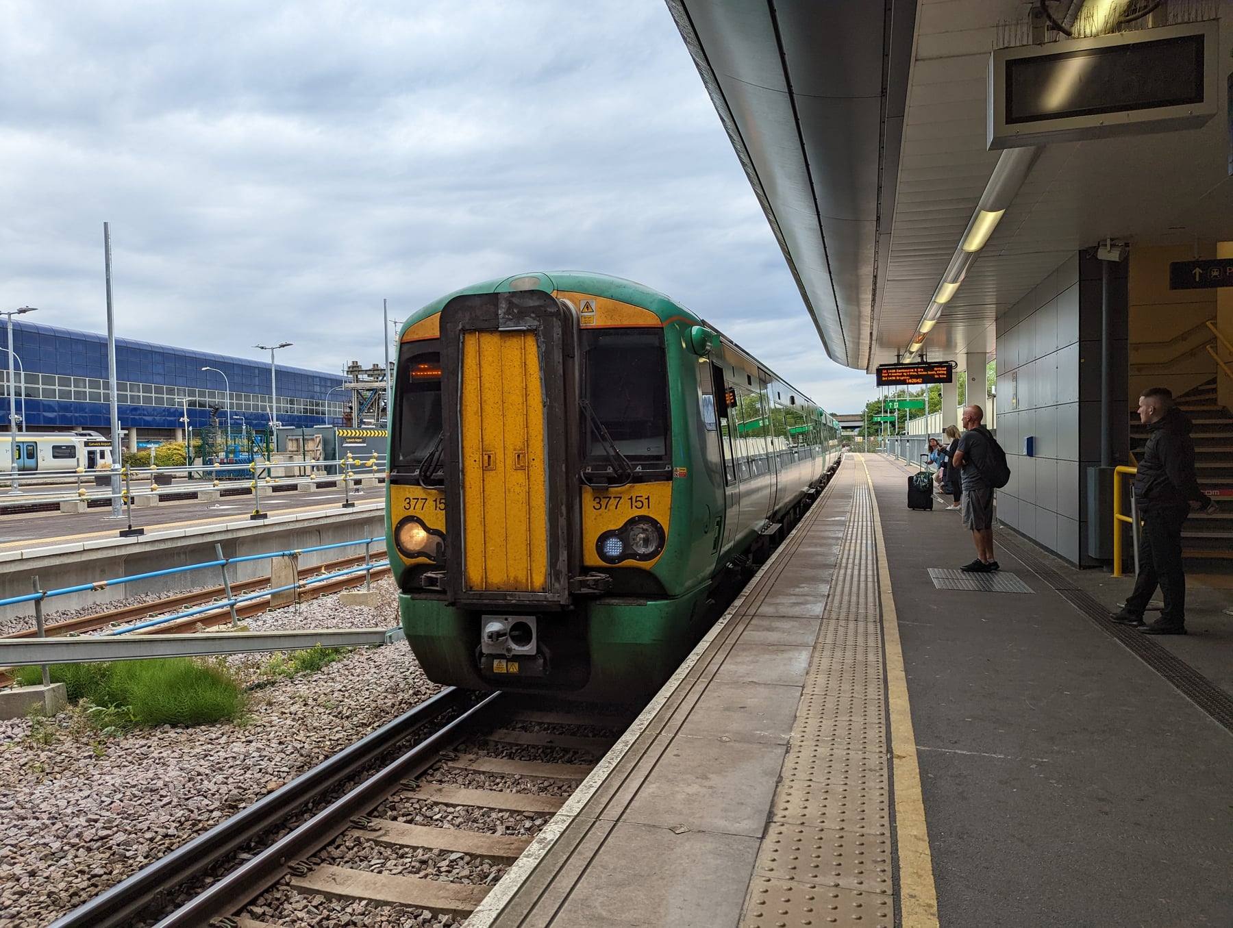 A green Southern Class 377 train at a platform at Gatwick Airport station